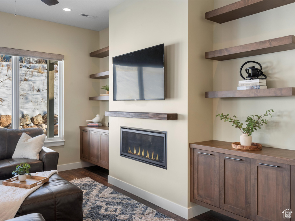 Living room featuring a glass covered fireplace, dark wood finished floors, baseboards, recessed lighting, and ceiling fan