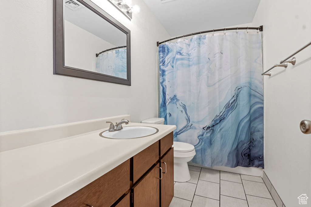 Full bathroom featuring toilet, vanity, tile patterned flooring, and curtained shower