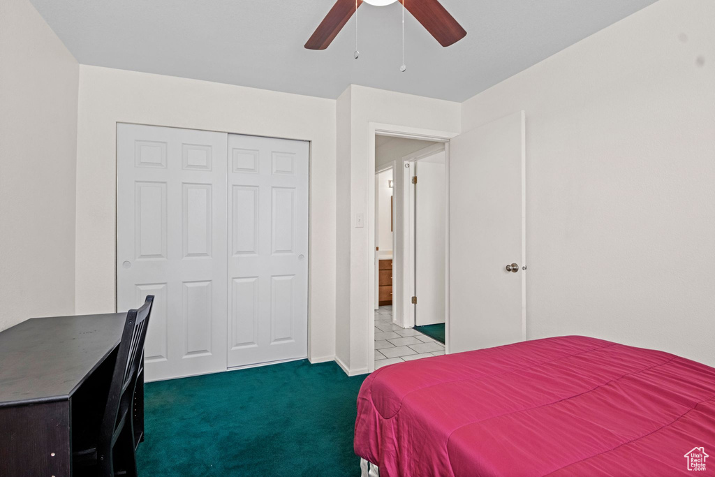 Carpeted bedroom with ceiling fan and a closet