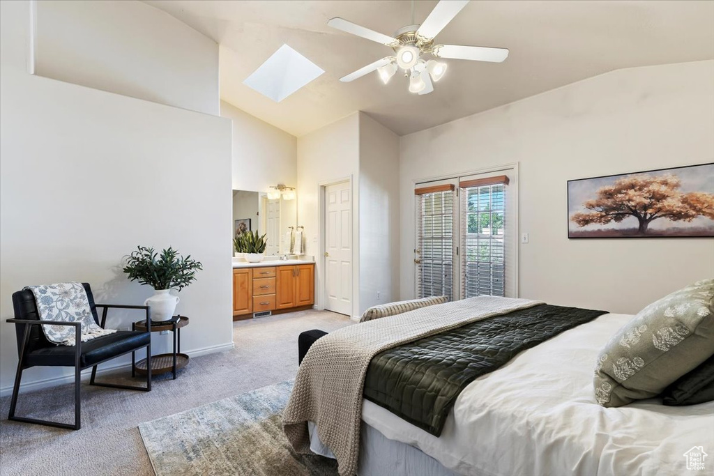 Bedroom featuring light colored carpet, a skylight, access to outside, high vaulted ceiling, and ensuite bath