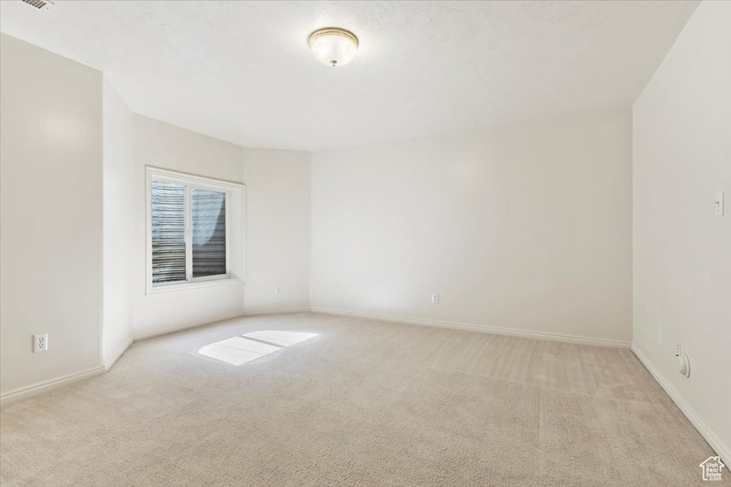 Unfurnished room featuring light colored carpet and baseboards
