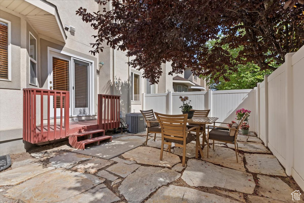 Fenced backyard with a patio area, outdoor dining area, and cooling unit