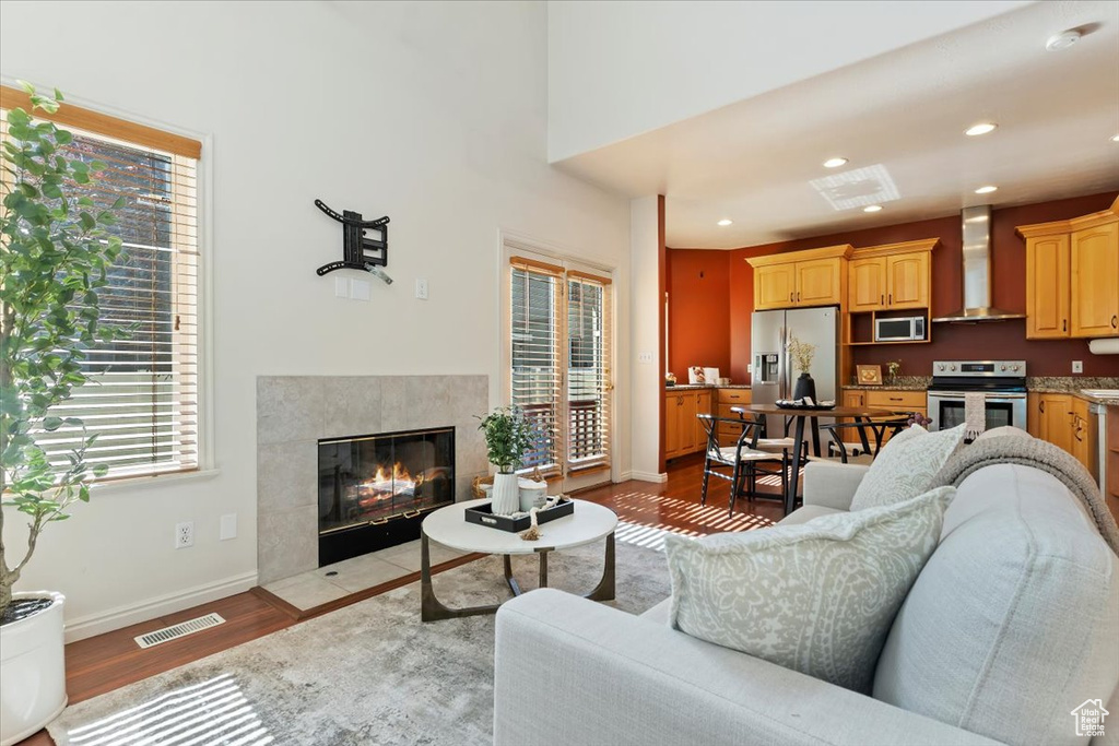 Living area featuring plenty of natural light, light wood-style flooring, a tile fireplace, baseboards, and recessed lighting