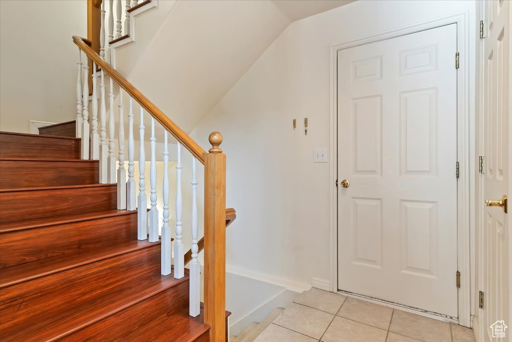Stairs with tile patterned flooring and vaulted ceiling