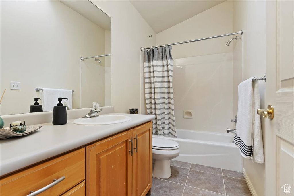 Full bathroom featuring vanity, shower / bathtub combination with curtain, toilet, tile patterned floors, and lofted ceiling