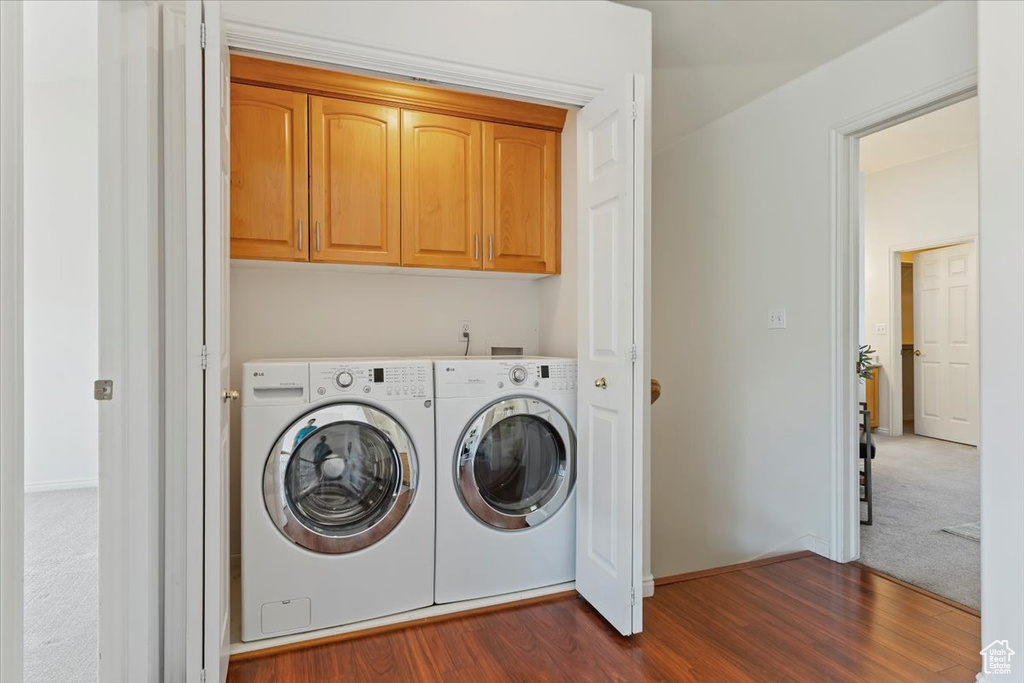 Laundry area featuring cabinet space, independent washer and dryer, dark wood-style floors, baseboards, and dark carpet