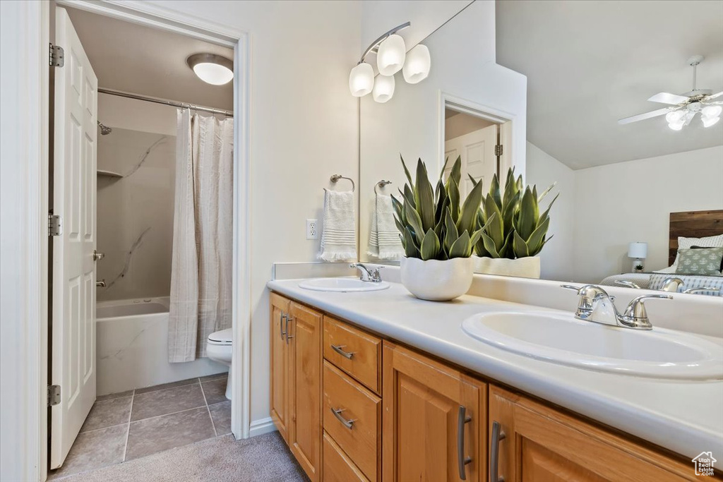Full bathroom featuring double vanity, shower / tub combo with curtain, ceiling fan, toilet, and tile patterned floors