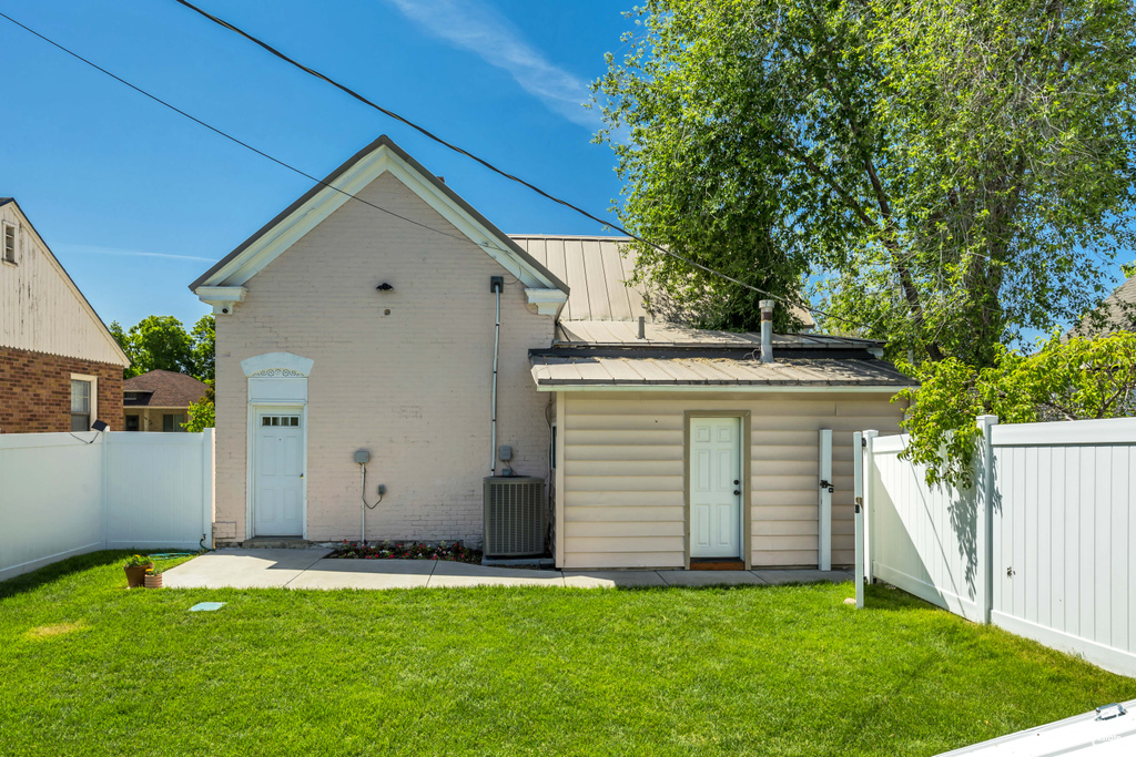 Rear view of house with central AC unit, brick siding, and metal roof