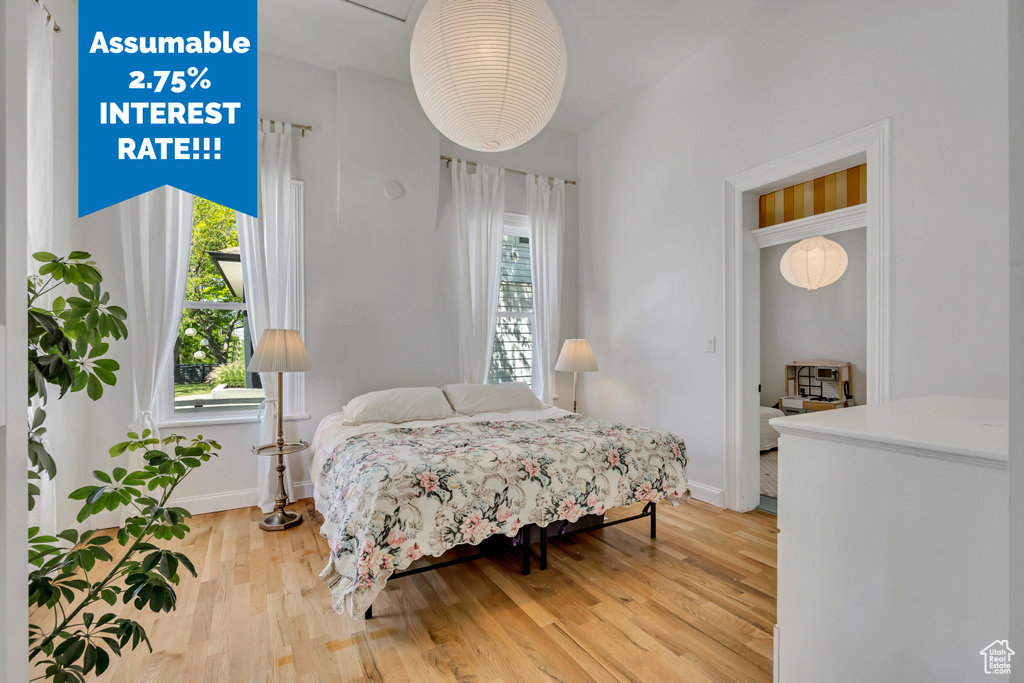 Bedroom with multiple windows, baseboards, and light wood-style floors