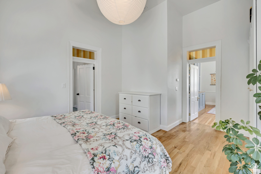 Bedroom with a high ceiling, light wood-style flooring, and baseboards