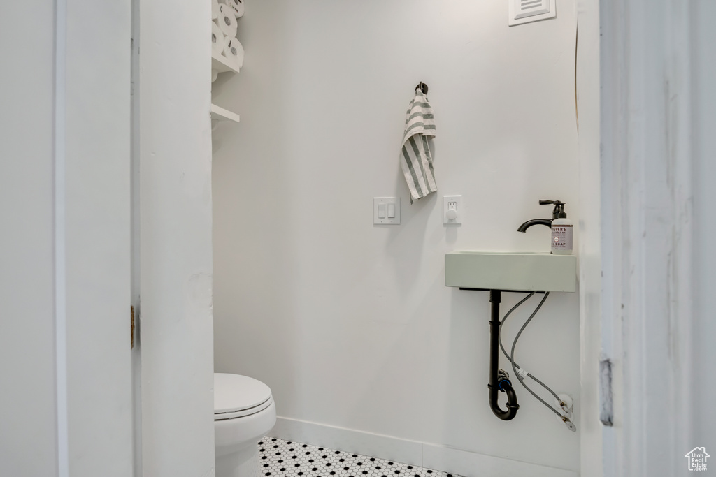 Bathroom with toilet, tile patterned floors, baseboards, and a sink