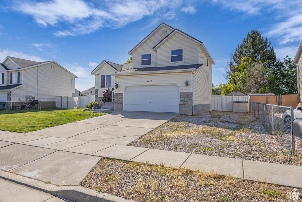 View of front of home with concrete driveway, a garage, a gate, and stone siding
