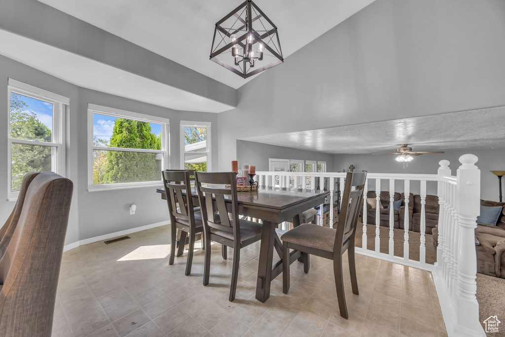 Dining area featuring plenty of natural light, baseboards, vaulted ceiling, a chandelier, and ceiling fan