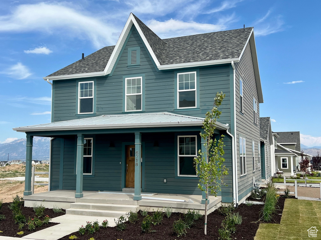 View of front of home featuring covered porch, roof with shingles, and a mountain view