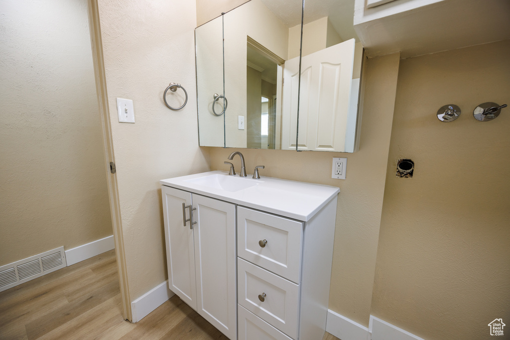 Bathroom with wood finished floors, vanity, and baseboards
