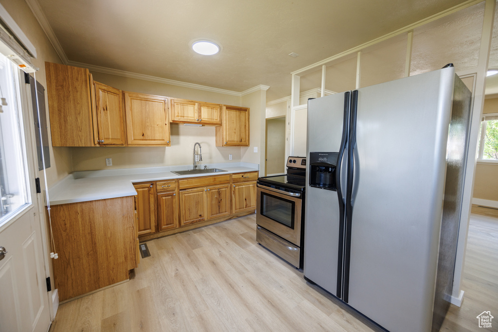 Kitchen with stainless steel appliances, a sink, light wood finished floors, light countertops, and ornamental molding