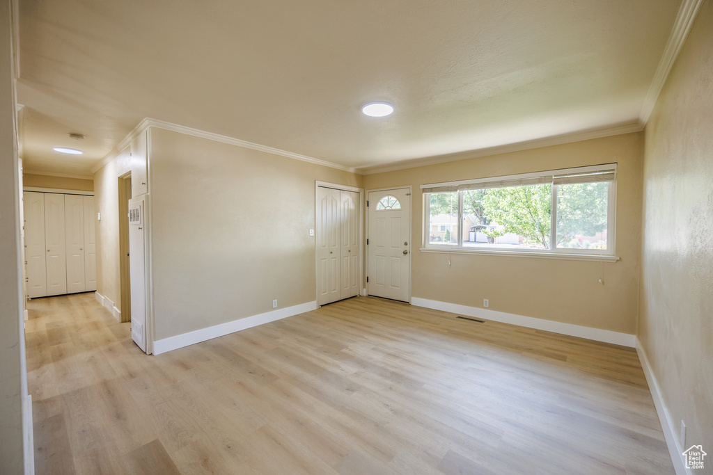 Entrance foyer featuring crown molding, light wood-style flooring, and baseboards