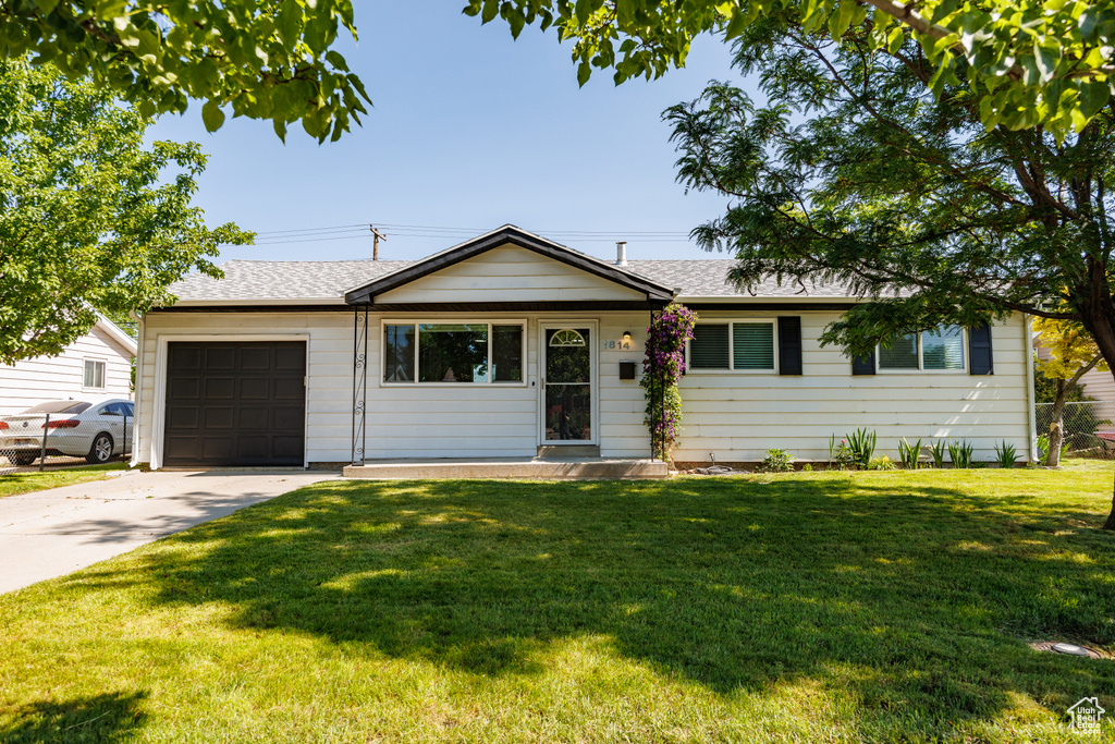 Ranch-style house with concrete driveway, an attached garage, roof with shingles, and a front yard
