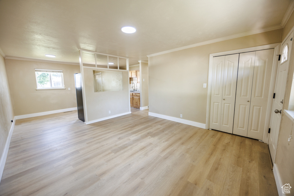 Unfurnished bedroom featuring ornamental molding, light wood-type flooring, baseboards, a closet, and a sink