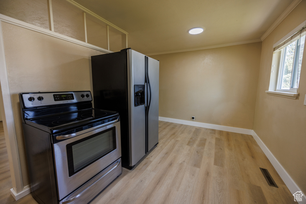 Kitchen featuring stainless steel appliances, light wood-type flooring, ornamental molding, and baseboards