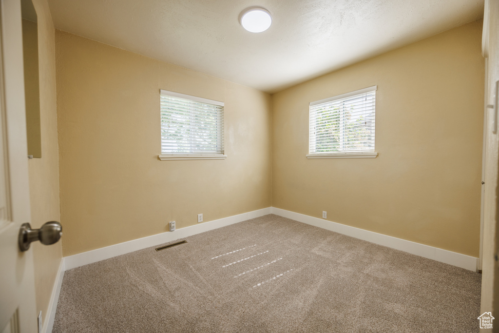 Carpeted spare room featuring baseboards