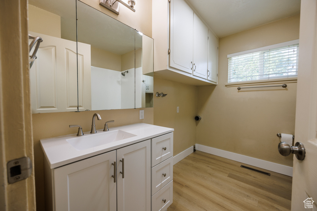 Laundry area with light wood-type flooring, baseboards, cabinet space, and washer hookup