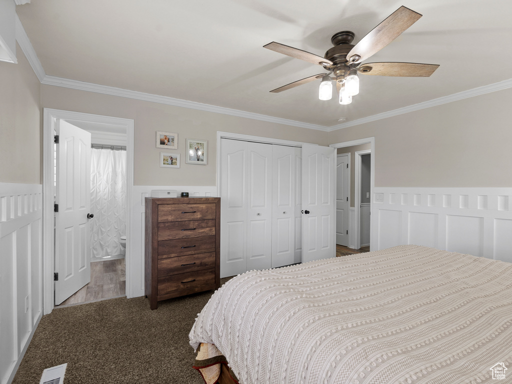 Bedroom featuring ornamental molding, wainscoting, a closet, a ceiling fan, and ensuite bath