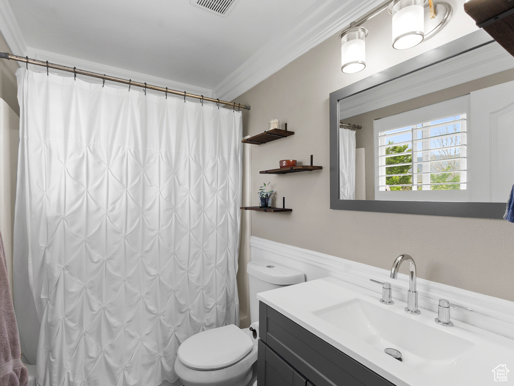 Full bathroom featuring ornamental molding, toilet, vanity, and curtained shower