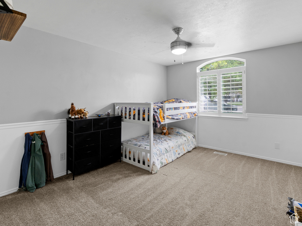 Carpeted bedroom with a ceiling fan