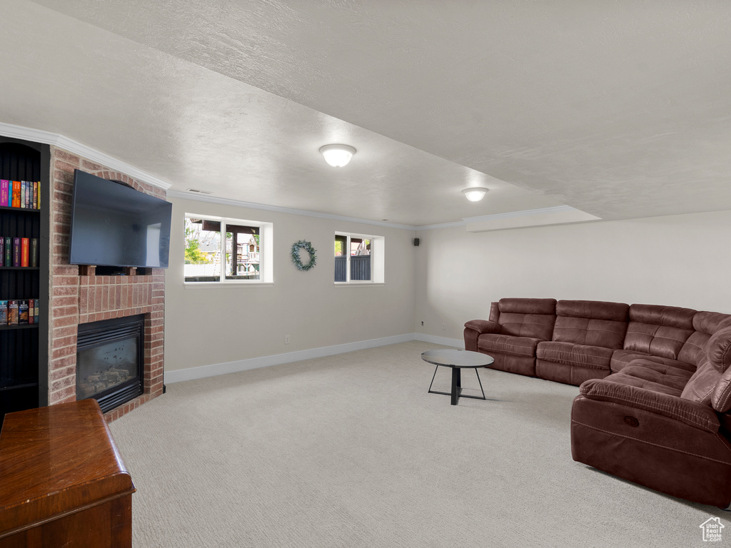Carpeted living room featuring a brick fireplace, baseboards, and crown molding
