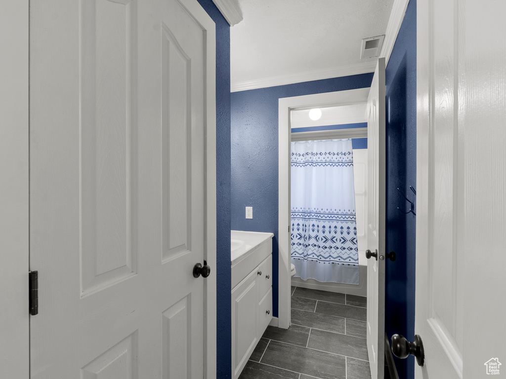 Full bathroom with crown molding, toilet, a shower with shower curtain, vanity, and a textured wall