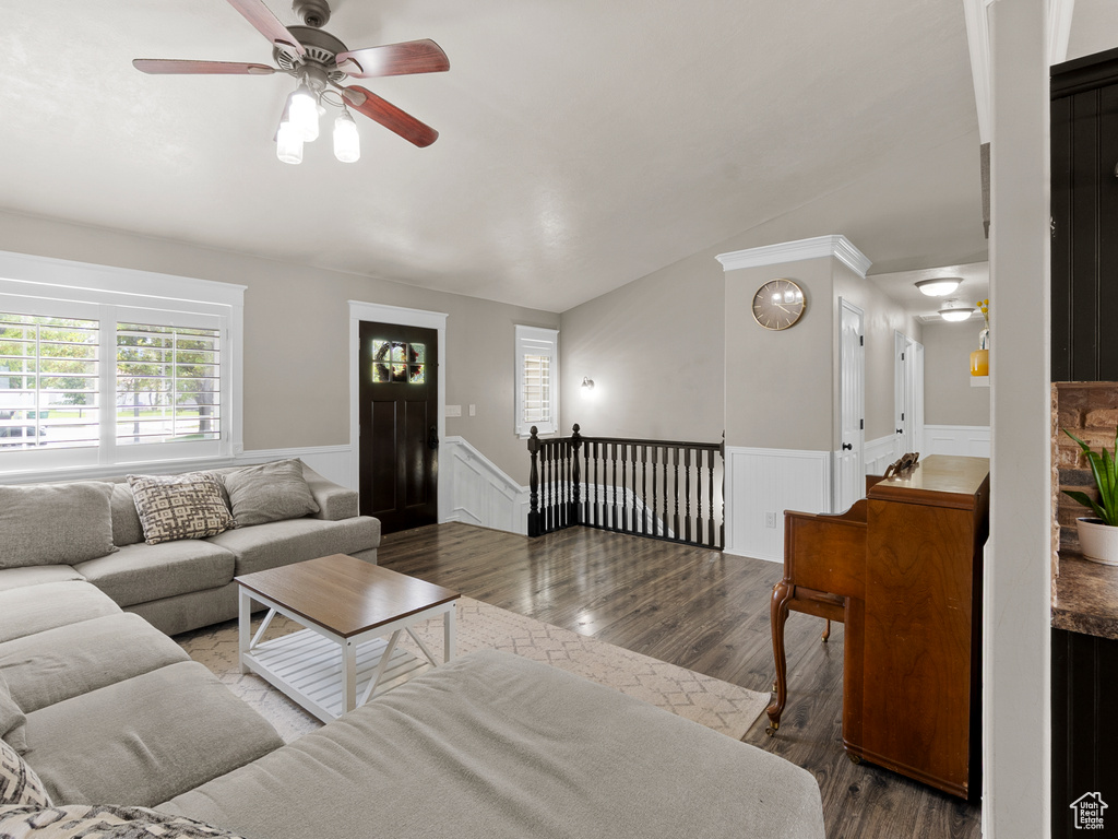 Living area with wainscoting, wood finished floors, ceiling fan, and vaulted ceiling