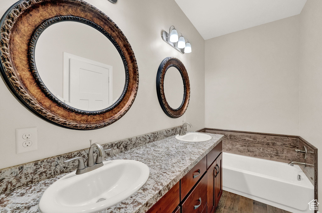Full bathroom with a bath, wood finished floors, and double vanity