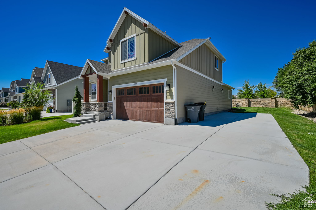 View of front of property featuring board and batten siding, an attached garage, concrete driveway, and a shingled roof