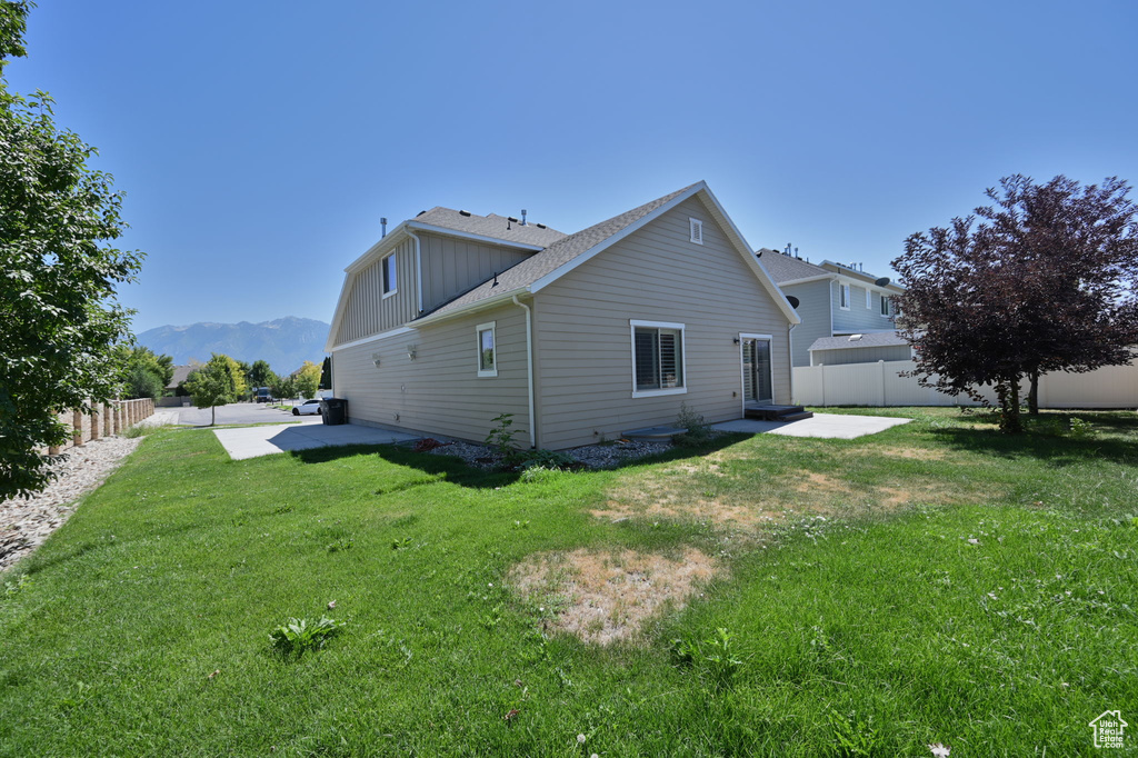 View of side of home with a patio, a mountain view, a shingled roof, and board and batten siding