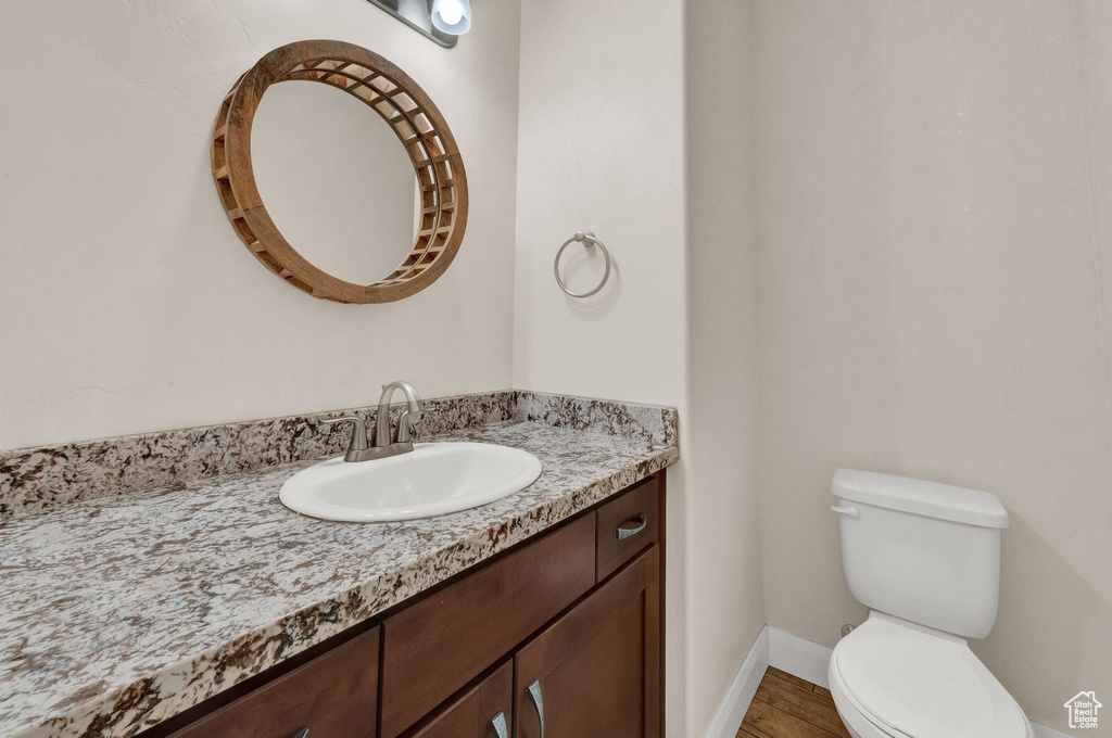 Bathroom with toilet, vanity, baseboards, and wood finished floors