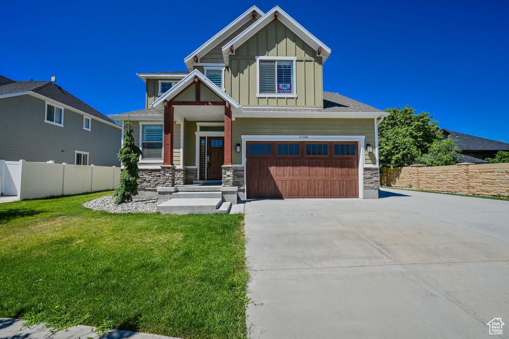 Craftsman inspired home featuring board and batten siding, a garage, concrete driveway, and stone siding