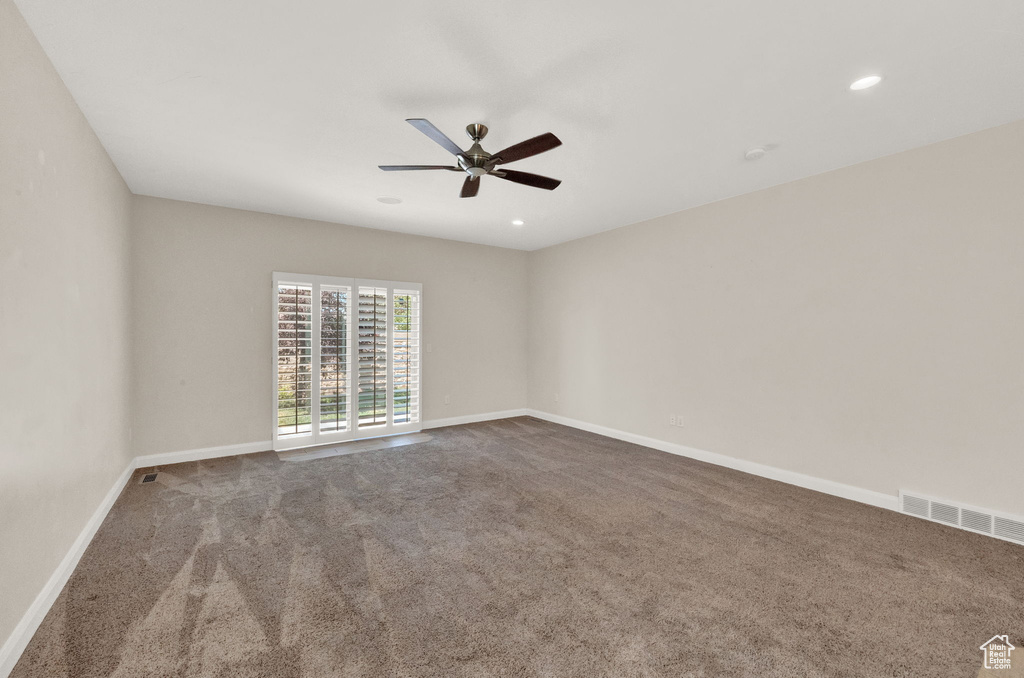 Carpeted empty room featuring ceiling fan, baseboards, and recessed lighting