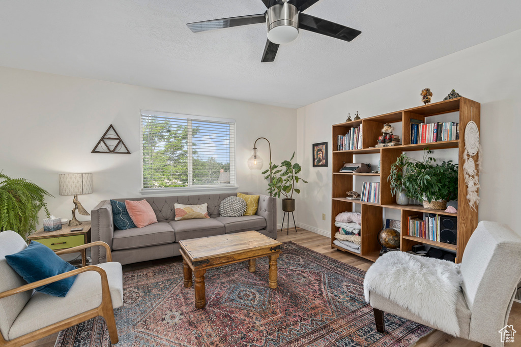Living area featuring ceiling fan, wood finished floors, and baseboards