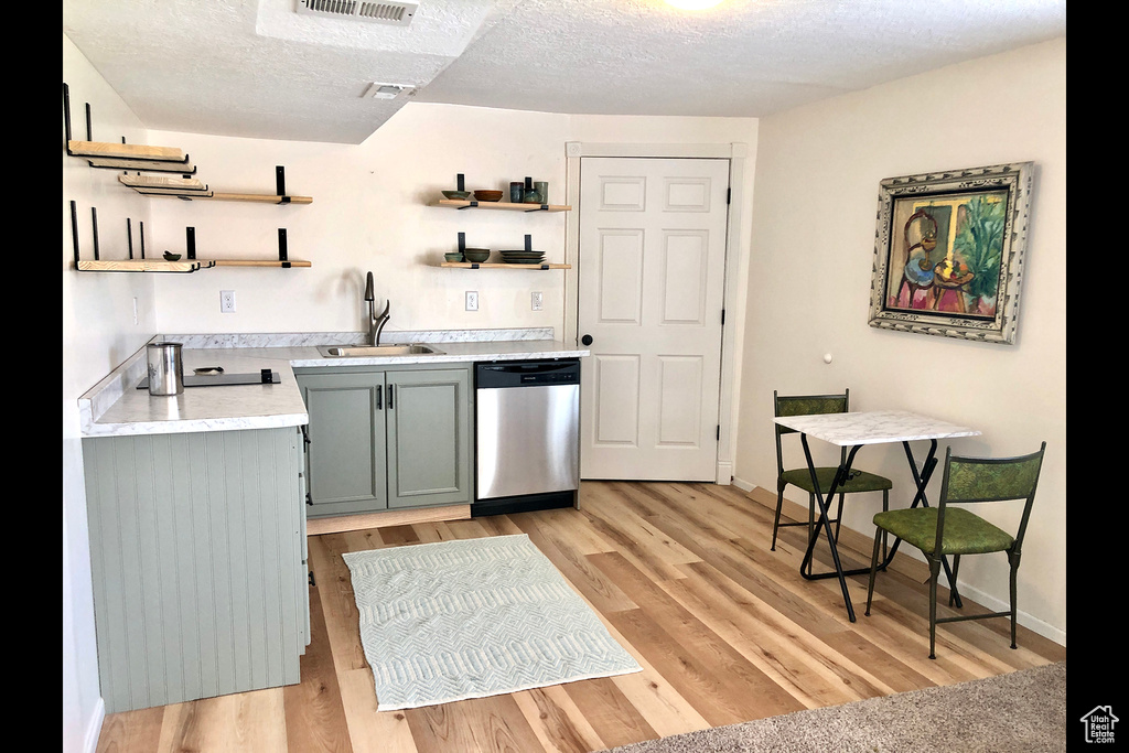 Kitchen featuring dishwasher, open shelves, a sink, light countertops, and a textured ceiling