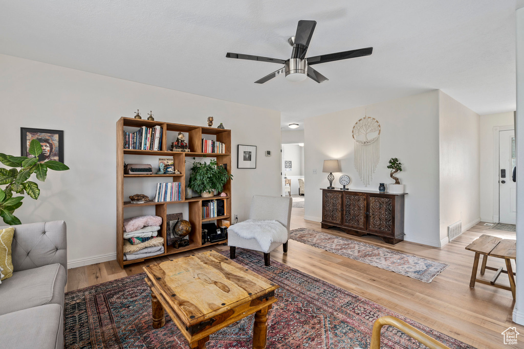 Living area with light wood-type flooring, ceiling fan, and baseboards