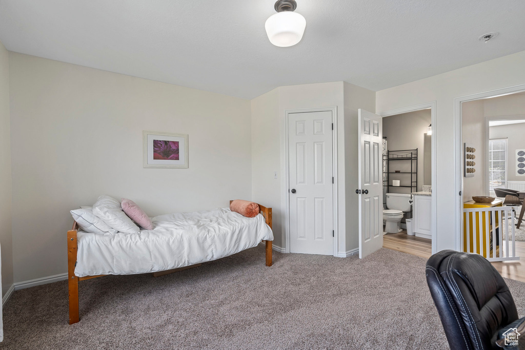 Bedroom with light carpet, baseboards, and ensuite bath
