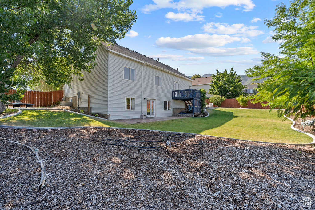 Rear view of house featuring a wooden deck and a patio