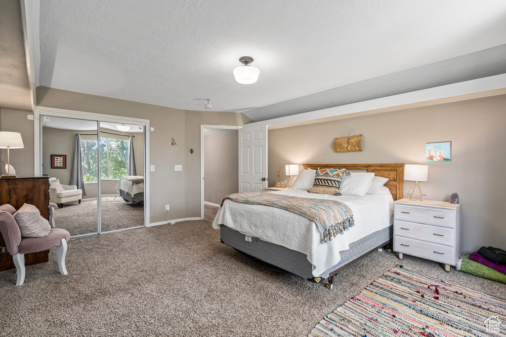 Carpeted bedroom featuring a textured ceiling and baseboards