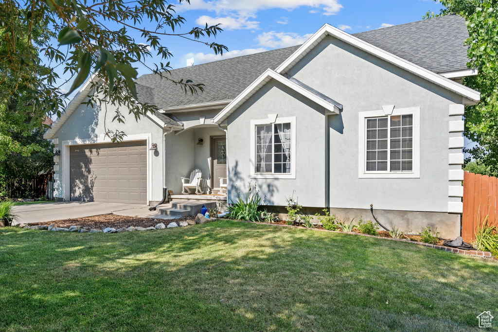 View of front of property featuring stucco siding, a garage, a shingled roof, and a front yard