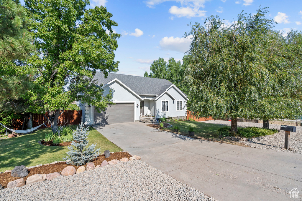 Ranch-style house with a garage, driveway, stucco siding, and roof with shingles