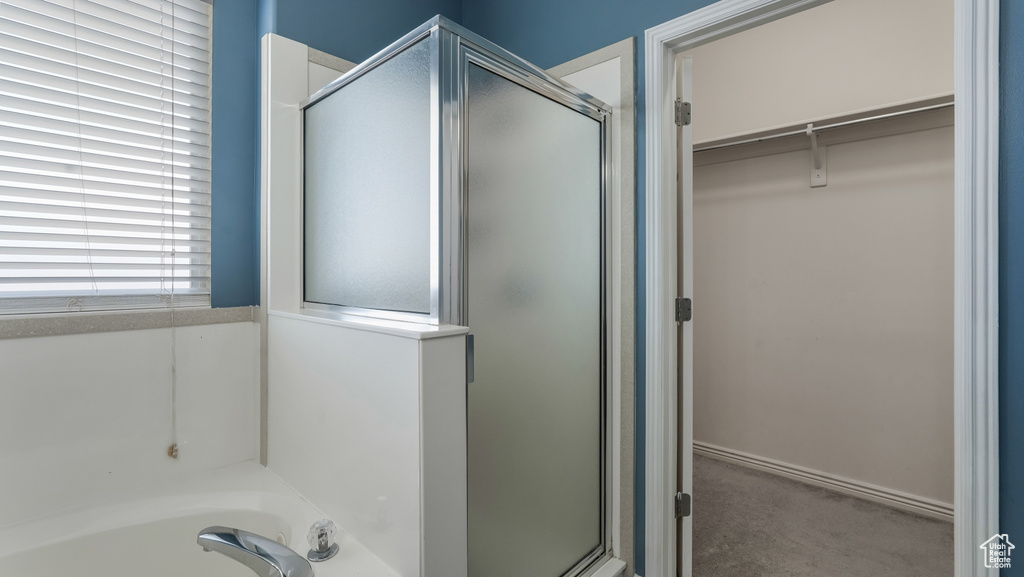 Full bathroom with a shower stall, a spacious closet, and a bath