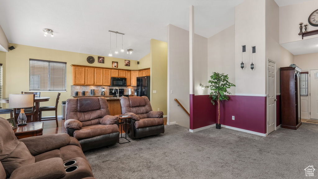 Living room with baseboards, light carpet, and high vaulted ceiling