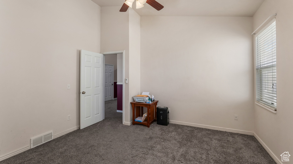 Carpeted empty room featuring ceiling fan and baseboards