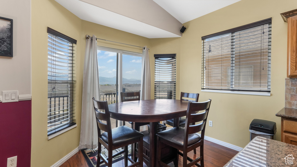 Dining space featuring dark wood-type flooring, a mountain view, baseboards, and vaulted ceiling
